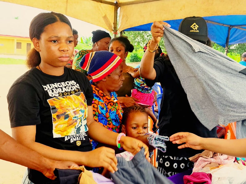 A young volunteer helping a mother and child select clothing